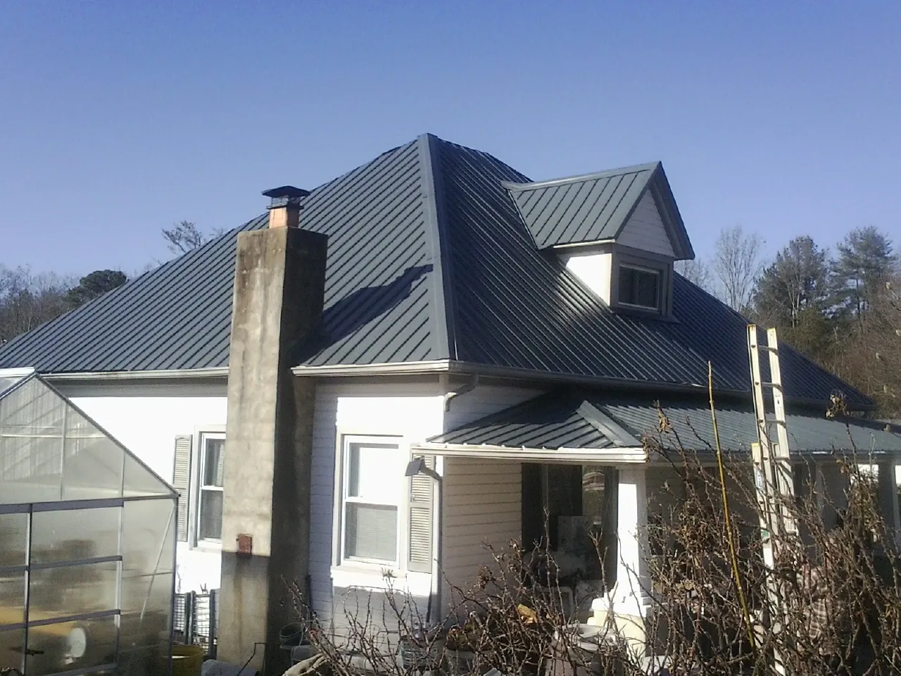 Dark blue standing seam metal roof on a white farmhouse with dormer — Slate & Tile Roof Repair by Roofing Brothers in Lambertville