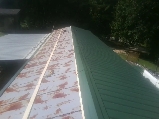 Old rusted panels beside newly installed green metal roofing — Wind Damage Roof Repair by Roofing Brothers in Lambertville