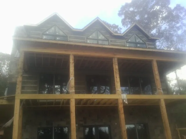 Dormers and porch framing on a large log home under construction — Roof Coating work by our crew in Lambertville