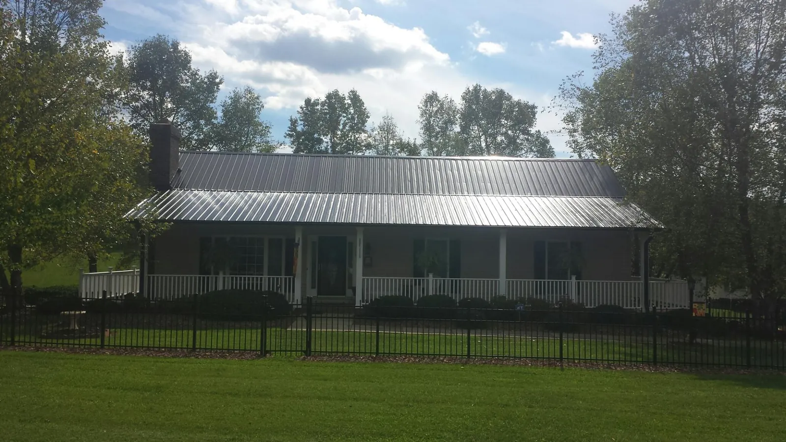 Gray metal roof on a brick ranch with a full width front porch — Gutter Guard Installation work by our crew in Lambertville