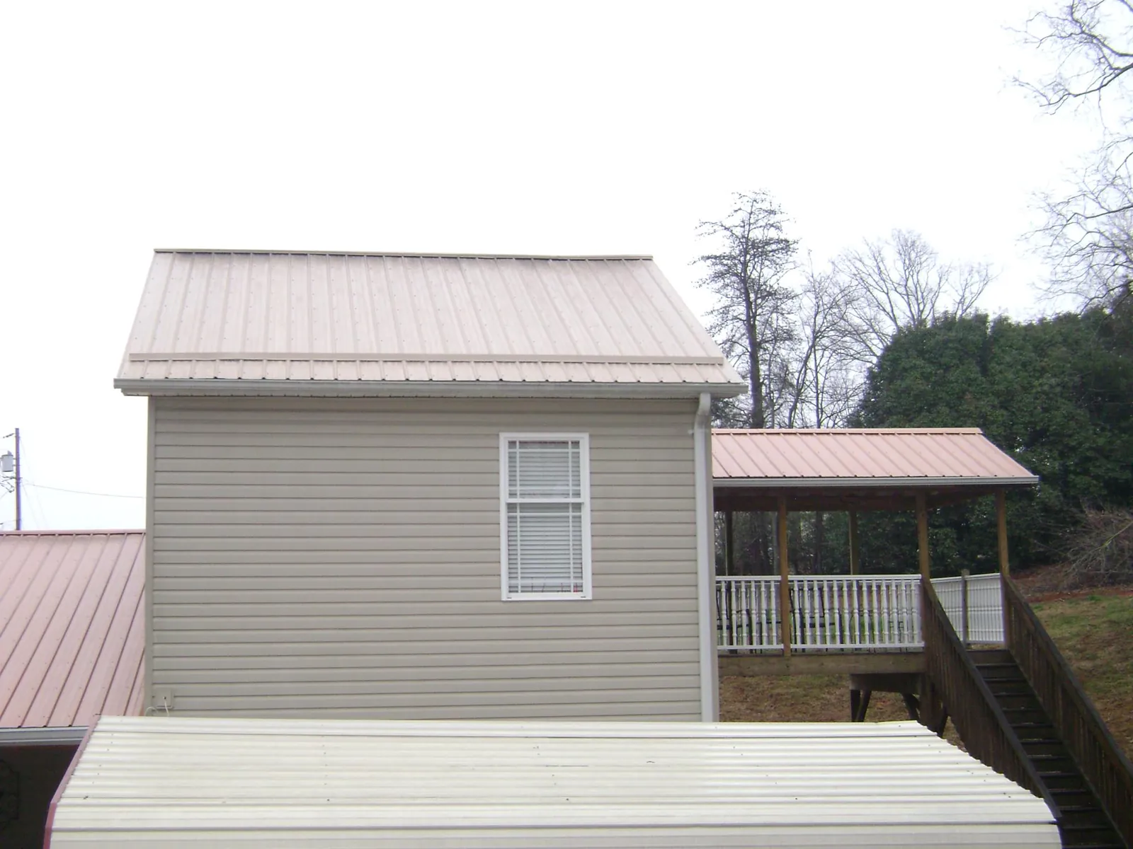 Tan metal roofs on a two story addition and attached porch, from a Roof Replacement job in Lambertville